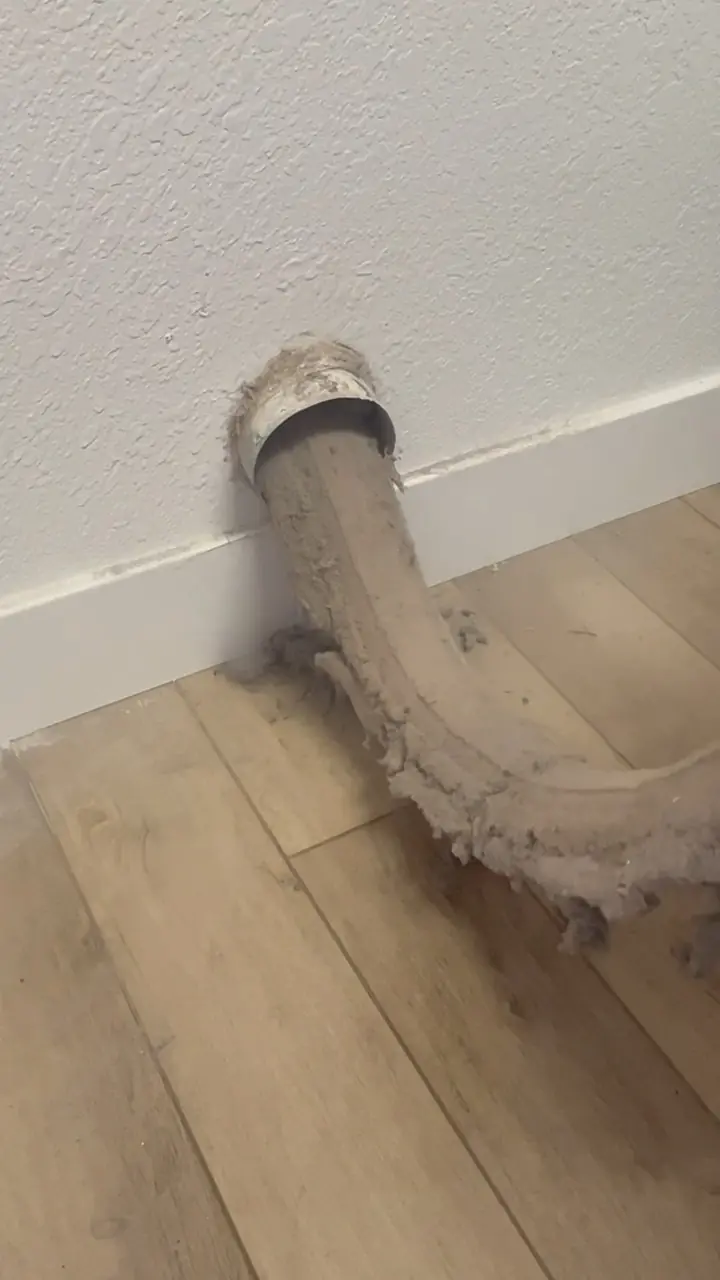 A dryer vent being cleaned, with the lint blockage coming loose